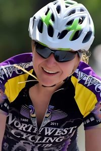 Cyclist wearing helmet and sunglasses, smiling during a bike ride with Northwest Cycling Club.