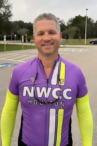 Smiling male cyclist in NWCC Houston cycling jersey outdoors, promoting local biking community.