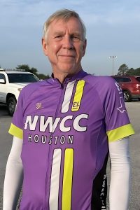 Happy male cyclist wearing NWCC Houston jersey during outdoor ride in parking lot.