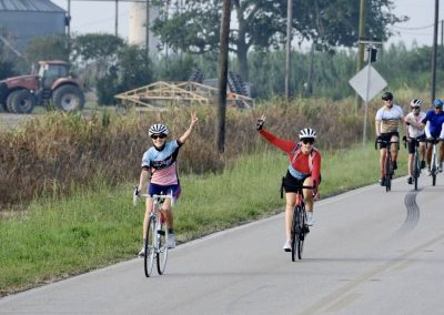 Katy Flatlands Century Bike Ride 8 Vegan cyclists riding on scenic rural road in Northwest Cycling Club event.