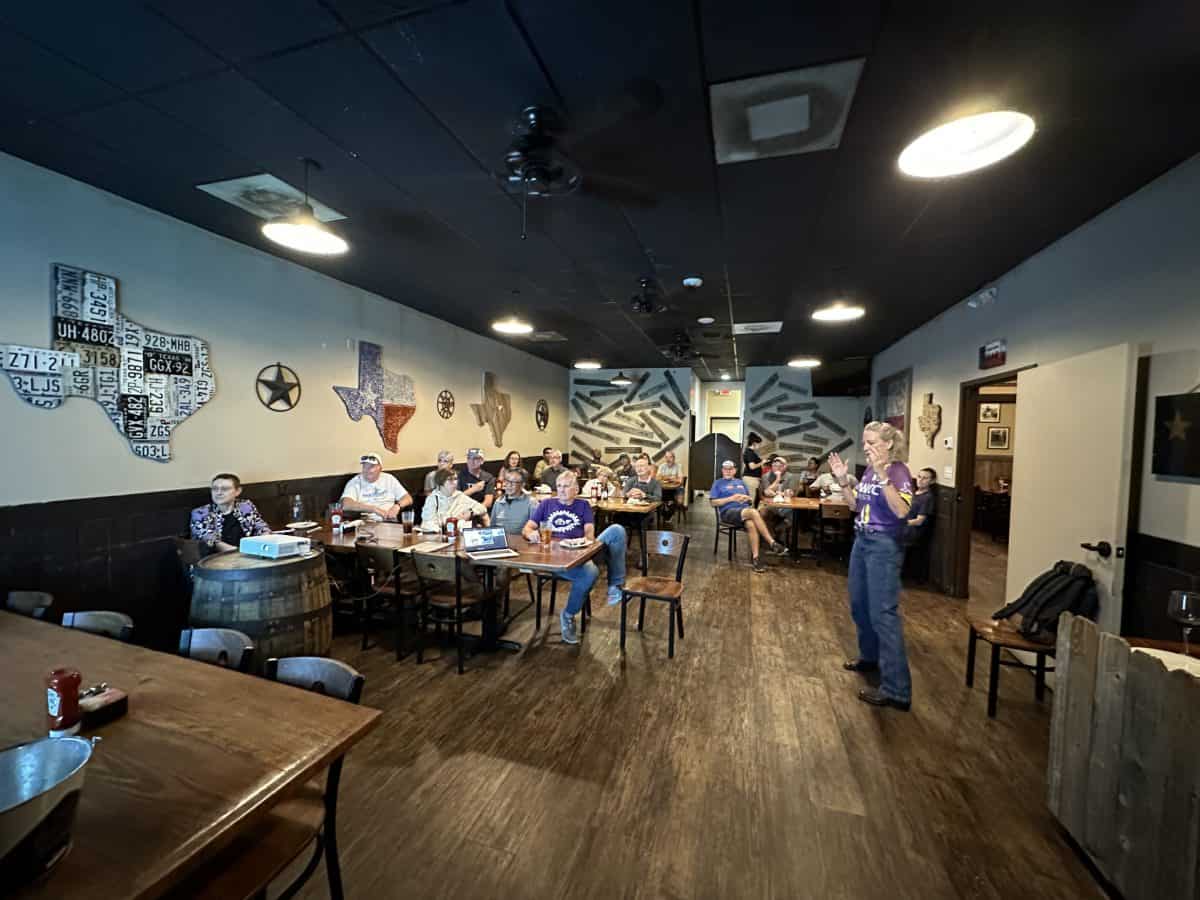 Group of cyclists at a company meeting or social event in a Texas-themed restaurant or bar.