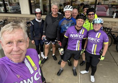 NWCC Vintage Park Starbucks Ride 38 Group of cyclists in NWCC Houston jerseys ready for a ride, smiling outside a storefront, showcasing community and cycling enthusiasm.