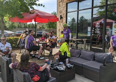 Outdoor scene of Northwest Cycling Club members relaxing outside a cafe after a cycling ride, showing community and cycling camaraderie.