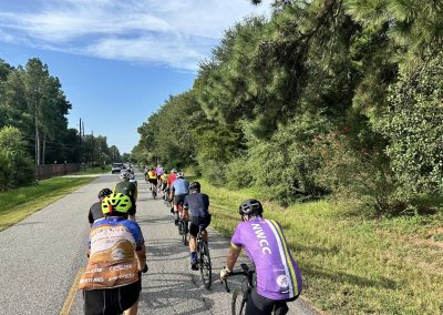 NWCC Vintage Park Starbucks Ride 50 Group of cyclists riding on scenic rural road with lush greenery, aligned for a community biking event.