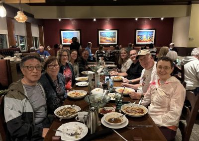 Friendly group enjoying a meal at a Northwest Cycling Club dinner event in a cozy restaurant setting.
