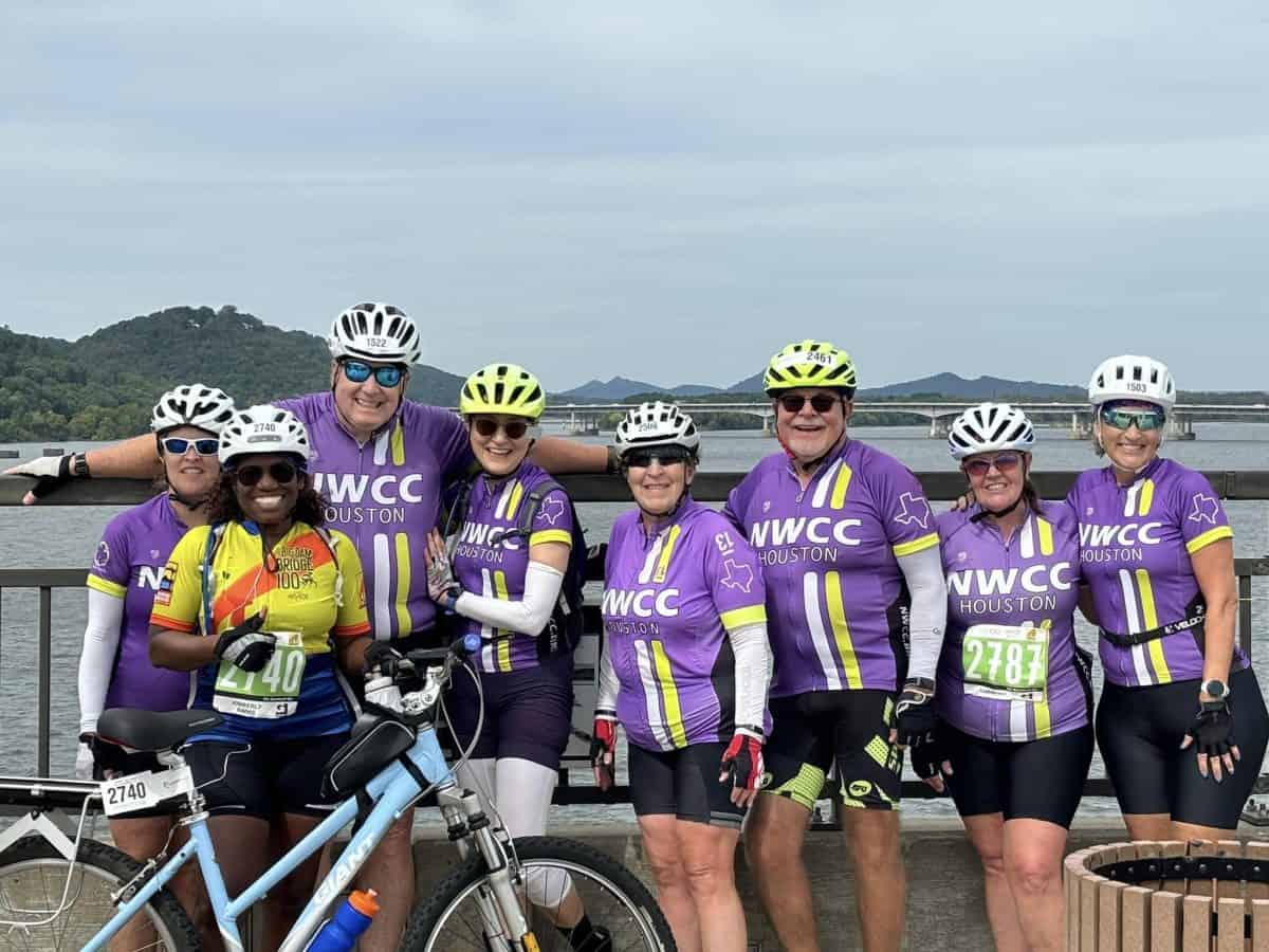 2024 Big Dam Bridge Group of cyclists wearing NWCC Houston jerseys posing together on a bridge for a cycling event.