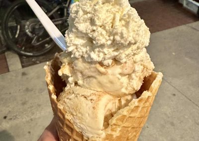 Creamy vanilla ice cream cone topped with whipped cream and cookie crumbs, perfect for summer.