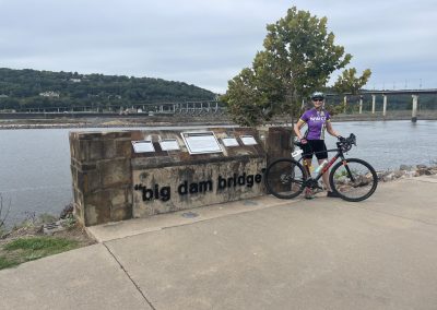 Scenic view of cyclist at Big Dam Bridge by the Arkansas River, part of Northwest Cycling Club's scenic biking route.