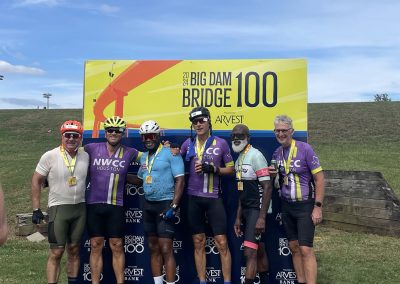 Cycling team celebrating at Big Dam Bridge 100 event, promoting fitness with Northwest Cycling Club in Houston.