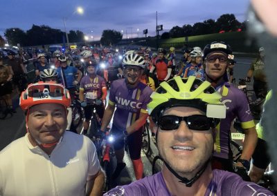 Group of cyclists at night during a Northwest Cycling Club event, wearing helmets and athletic gear.