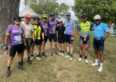 Group of cyclists wearing NWCC Houston jerseys at a cycling event, enjoying outdoor scenery.