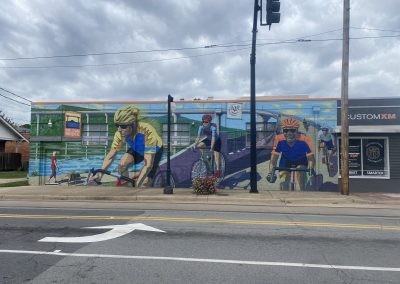 Vibrant mural of cyclists riding by a river, promoting Northwest Cycling Club community events.