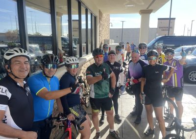 Cycling In Houston - NWCC Recent Activities Gallery 661 Group of cyclists smiling in cycling gear outside a cafe, promoting Northwest Cycling Club and group riding.