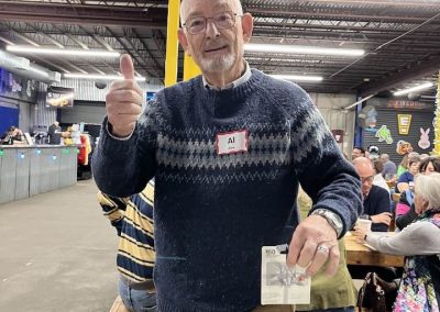 Cycling In Houston - NWCC Recent Activities Gallery 657 Older man giving thumbs up at indoor cycling club event, casual attire, social gathering.