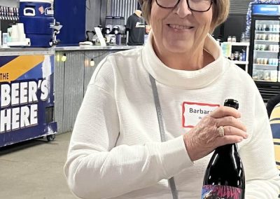 Cycling In Houston - NWCC Recent Activities Gallery 658 Colorful craft beer bottle held by smiling woman at Northwest Cycling Club event.