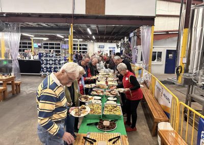 Cycling In Houston - NWCC Recent Activities Gallery 608 Group of seniors enjoying a buffet at Northwest Cycling Club event in a brewery or warehouse.