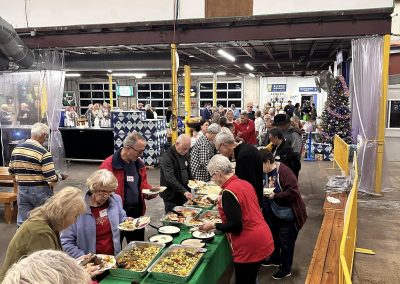 Cycling In Houston - NWCC Recent Activities Gallery 607 Community gathering at Northwest Cycling Club holiday event, enjoying festive food and camaraderie in a vibrant indoor setting.