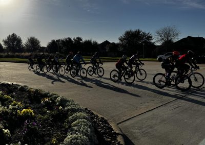 Cycling In Houston - NWCC Recent Activities Gallery 581 Group of cyclists riding on the street during sunset, promoting community cycling events.
