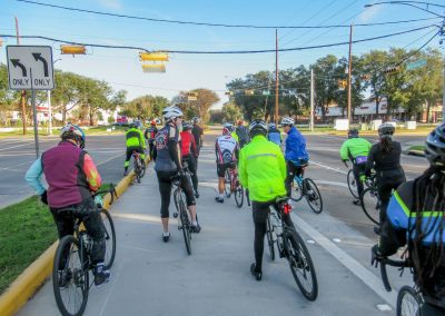 Cycling In Houston - NWCC Recent Activities Gallery 576 Cycling group crossing at traffic light during Northwest Cycling Club event in urban setting.