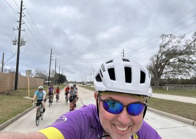 Cycling In Houston - NWCC Recent Activities Gallery 564 Vibrant group cycling ride with Northwest Cycling Club, featuring smiling cyclist in purple jersey and safety gear.