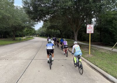 Cycling In Houston - NWCC Recent Activities Gallery 507 Cycling group riding on a scenic city street with trees, part of Northwest Cycling Club activities.