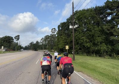 Cycling In Houston - NWCC Recent Activities Gallery 492 Group of cyclists riding on scenic rural road with lush green trees, promoting Northwest Cycling Club outdoor biking activities.