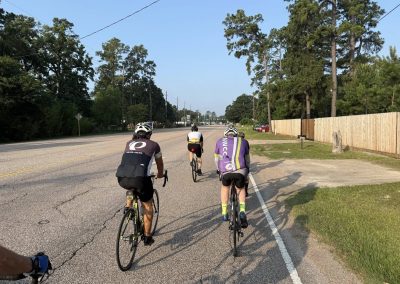 Cycling In Houston - NWCC Recent Activities Gallery 481 Active cyclists riding on a scenic road with trees in the background, promoting Northwest Cycling Club and outdoor cycling events.