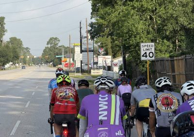 Cycling In Houston - NWCC Recent Activities Gallery 467 Cyclists riding together with NWCC jerseys on a city street, promoting community cycling events.