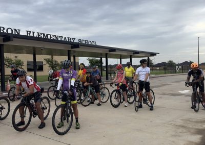 Cycling In Houston - NWCC Recent Activities Gallery 445 Group of cyclists gathering outside Northwest Cycling Club at elementary school, ready for a bike ride.