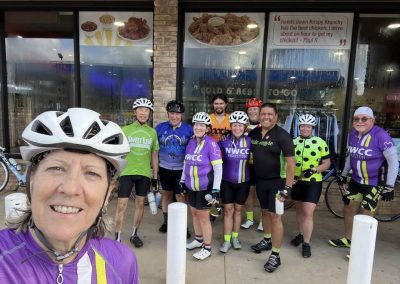 Cycling In Houston - NWCC Recent Activities Gallery 429 Cycling club members in colorful jerseys at NWCC meet-up in front of a restaurant.