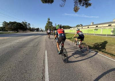 Cycling In Houston - NWCC Recent Activities Gallery 410 Group of cyclists riding on city street with clear sky, promoting Northwest Cycling Club.