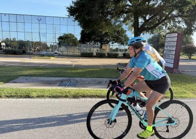 Cycling In Houston - NWCC Recent Activities Gallery 397 Cyclist riding a bike near Northwest Cycling Club building, promoting cycling and outdoor fitness.