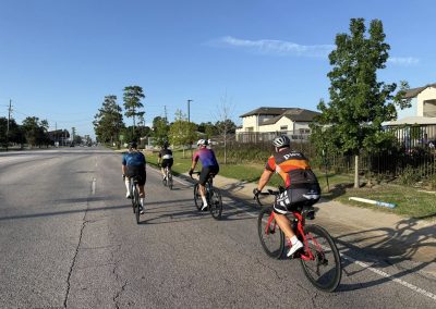 Cycling In Houston - NWCC Recent Activities Gallery 420 Cyclists riding together in a Northwest Cycling Club group ride on a sunny urban street.