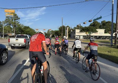Cycling In Houston - NWCC Recent Activities Gallery 392 Cycling group riding on city street with northwest scenery, participating in Northwest Cycling Club event.