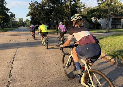 Cycling In Houston - NWCC Recent Activities Gallery 383 Group of cyclists riding together on a suburban street in the early morning; strong community vibe.