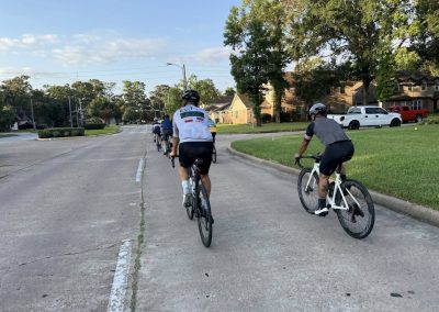 Cycling In Houston - NWCC Recent Activities Gallery 373 Cyclists riding together on a neighborhood street, part of Northwest Cycling Club outdoor activities.