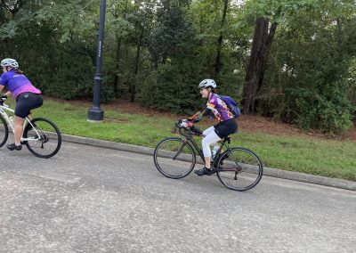 Cycling In Houston - NWCC Recent Activities Gallery 334 Women cycling on a scenic trail with lush green trees in the background for Northwest Cycling Club SEO.