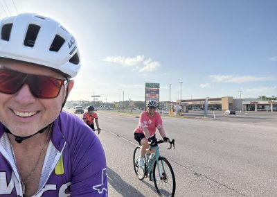 Cycling In Houston - NWCC Recent Activities Gallery 346 Vibrant cycling group riding on city street with Northwest Cycling Club banners, promoting active outdoor lifestyles.