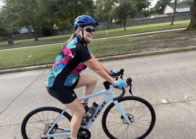Cycling In Houston - NWCC Recent Activities Gallery 326 Vibrant female cyclist riding a road bike during outdoor cycling event, promoting fitness and community.