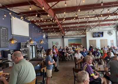 Cycling In Houston - NWCC Recent Activities Gallery 241 Indoor social gathering at Northwest Cycling Club's event, with cyclists enjoying food and drinks.