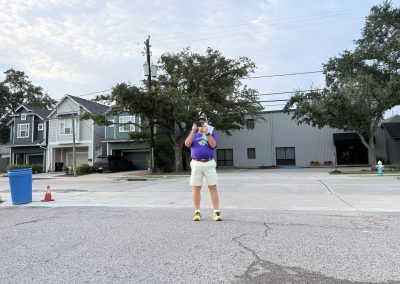 Cycling In Houston - NWCC Recent Activities Gallery 315 Man taking a photo in front of residential neighborhood during daytime, Northwest Cycling Club member, outdoor cyclist, urban cycling scene.