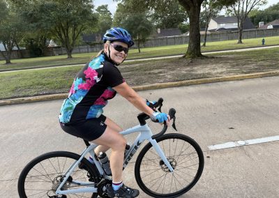 Cycling In Houston - NWCC Recent Activities Gallery 328 Vegan cyclist riding a road bike in a neighborhood with trees and houses in the background.
