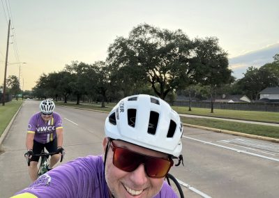 Cycling In Houston - NWCC Recent Activities Gallery 329 Colorful cyclists riding in Northwest Cycling Club event on a sunny suburban street, smiling and enjoying the ride.