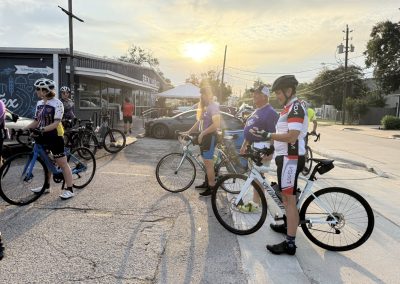 Cycling In Houston - NWCC Recent Activities Gallery 303 Cyclists gathering for a Northwest Cycling Club ride at sunset in a commercial parking lot.