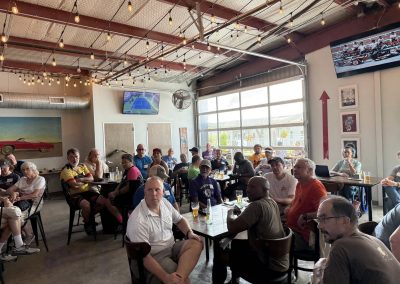 Cycling In Houston - NWCC Recent Activities Gallery 250 Indoor gathering of members at Northwest Cycling Club event with large windows and bike-themed decor.