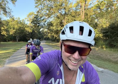Cycling In Houston - NWCC Recent Activities Gallery 223 Smiling cyclist taking a selfie with a group on a scenic park trail during a Northwest Cycling Club ride.