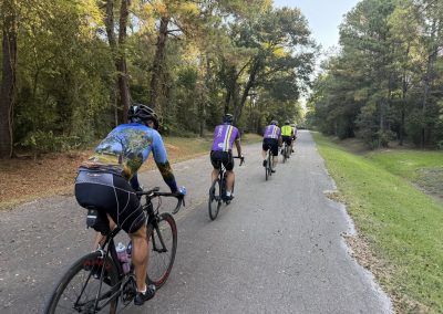 Cycling In Houston - NWCC Recent Activities Gallery 220 Cycling group riding on scenic trail with lush trees, part of Northwest Cycling Club outdoor activities.