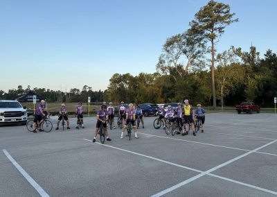 Cycling In Houston - NWCC Recent Activities Gallery 226 Group of cyclists in NWCC bike club jerseys in a parking lot ready for a ride, promoting community cycling events.
