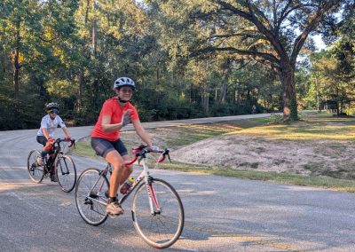 Cycling In Houston - NWCC Recent Activities Gallery 198 Biking group riding through scenic park with trees and winding road, showcasing Northwest Cycling Club’s outdoor cycling events.