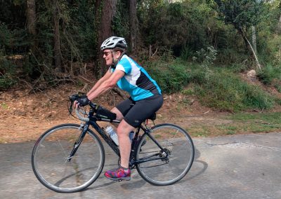 Cycling In Houston - NWCC Recent Activities Gallery 194 Scenic cyclist riding a bike through a lush forest trail for outdoor cycling enthusiasts.